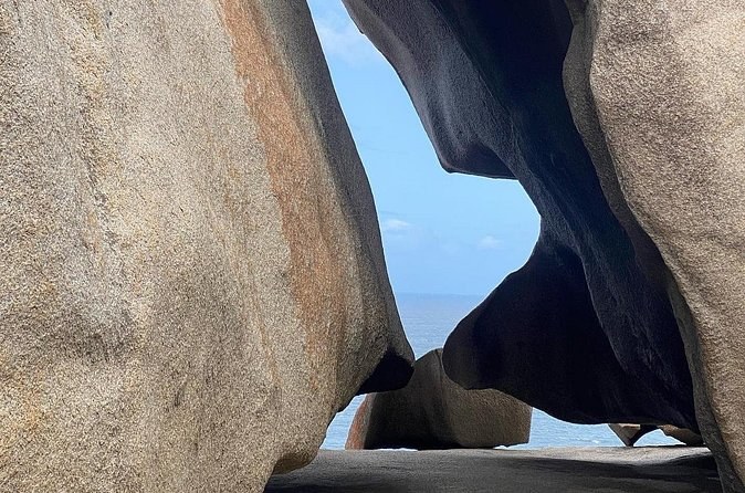 The hollowed underside of a weathered granite boulder against a blue sky